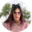 Person mit Brille und Haaraccessoire, lächelt im Freien