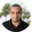A man with a black shirt and trees in the background