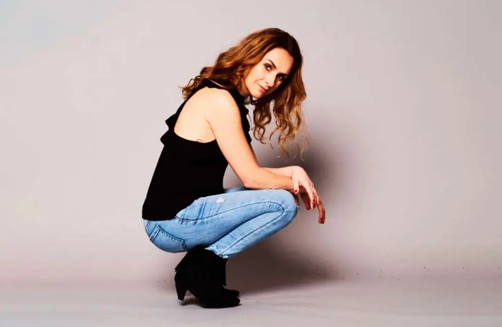 Woman squatting in blue jeans and black top