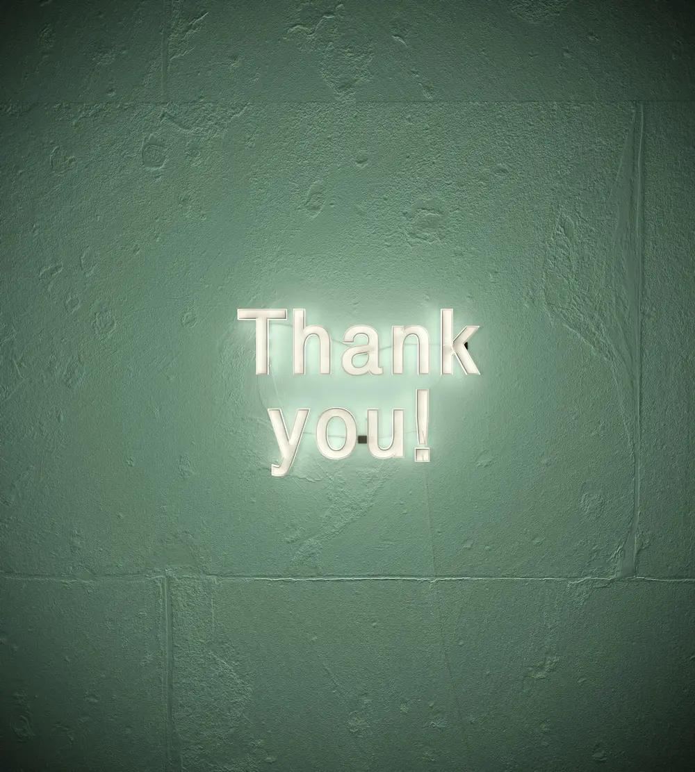 Cartel de gracias iluminado en una pared verde con textura