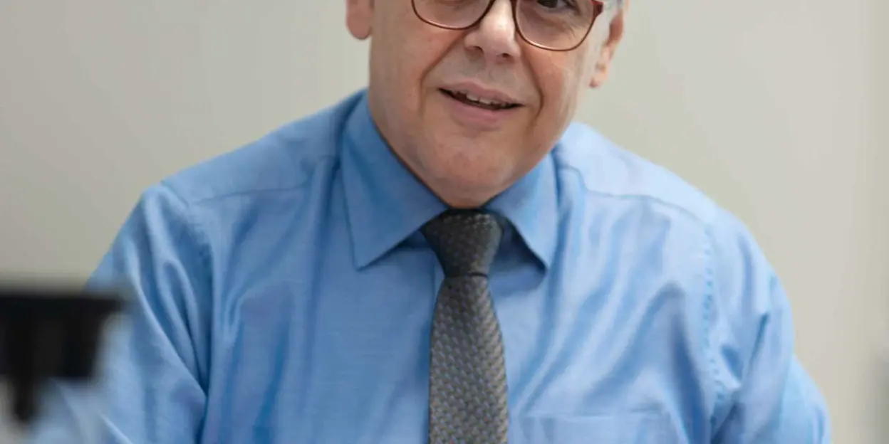 Mann mit Brille und blauem Hemd am Schreibtisch