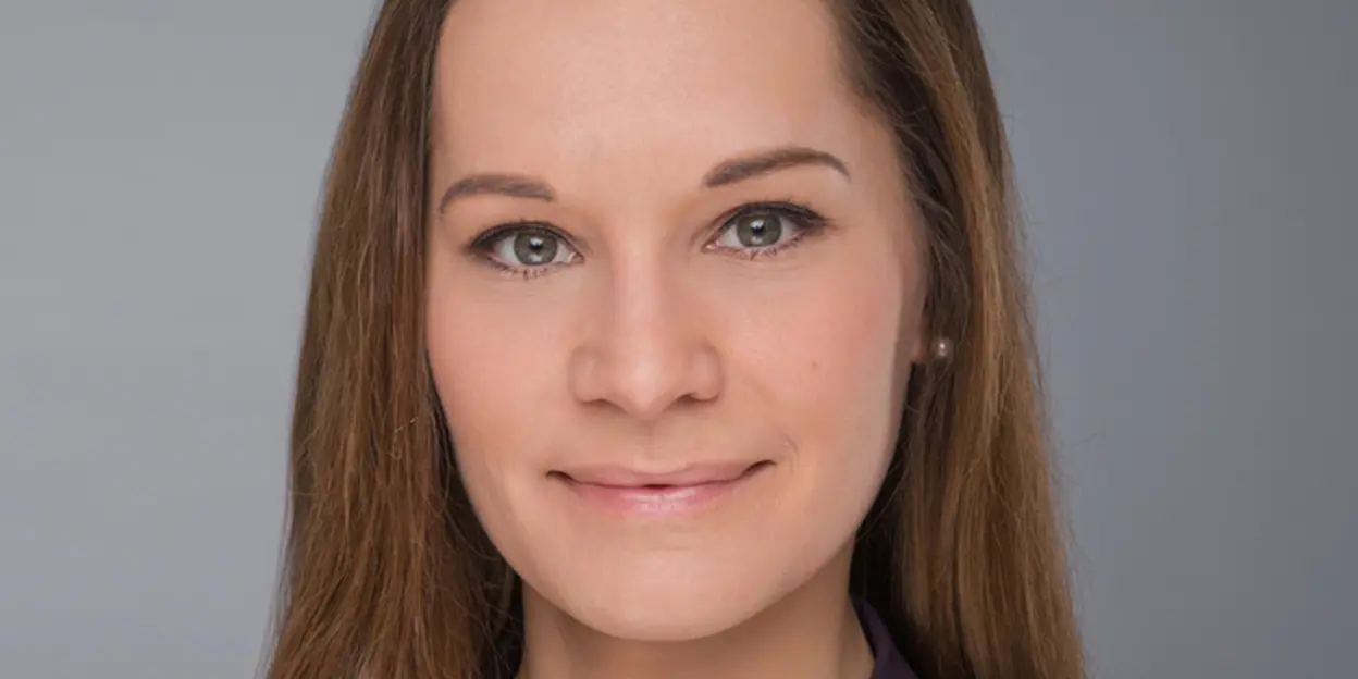 Headshot of a woman with long brown hair in a purple top