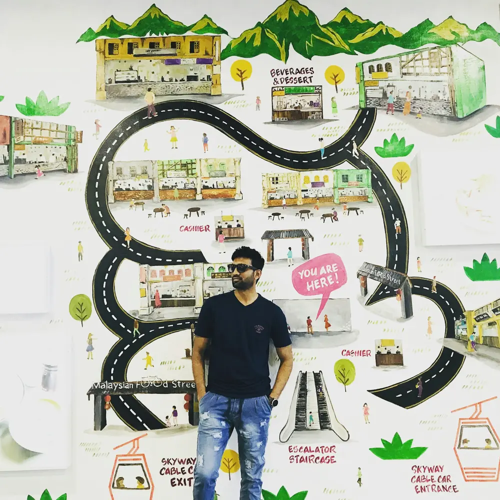 Man standing in front of a colorful mural featuring a map and various buildings.