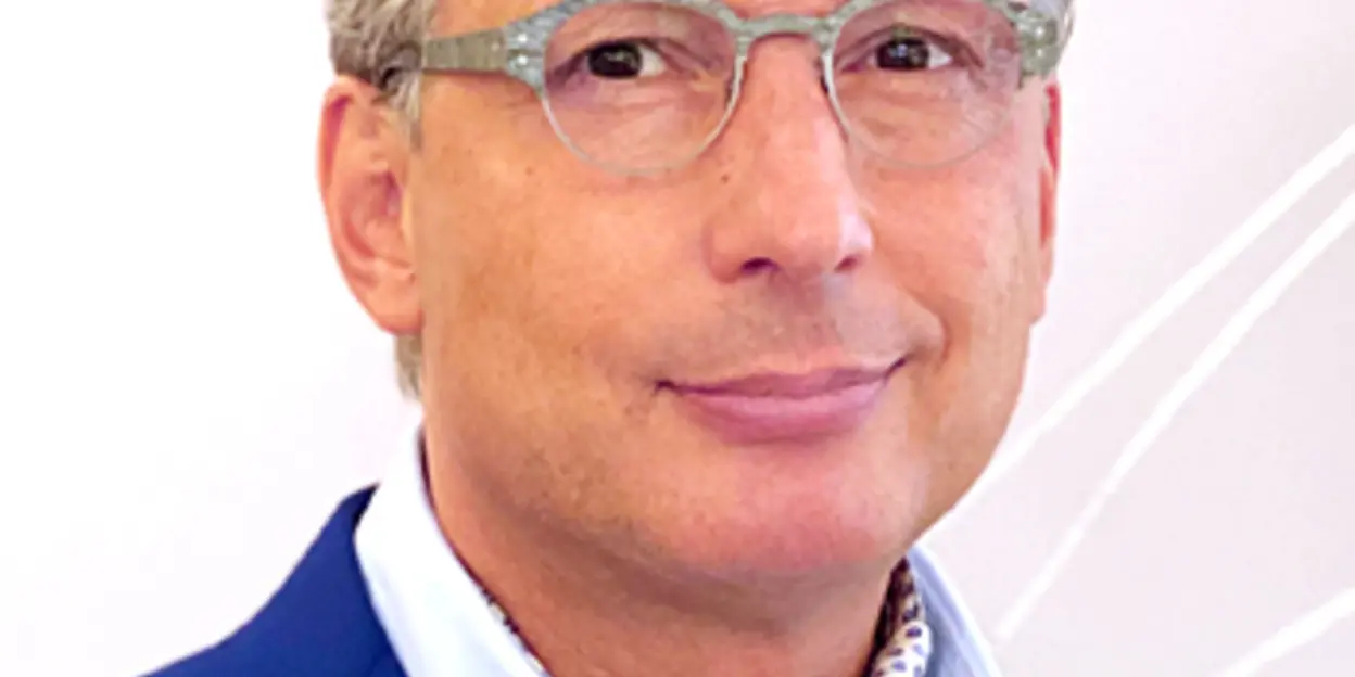 Man wearing a blue suit, glasses, and a polka dot scarf