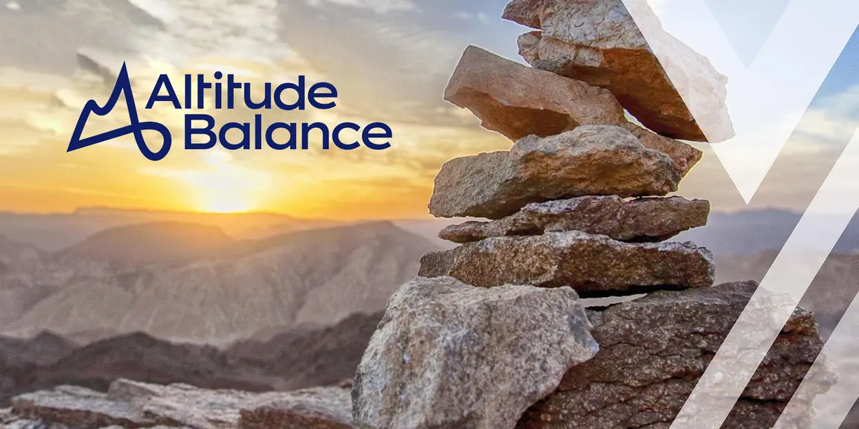A stack of balanced rocks against a mountain sunset