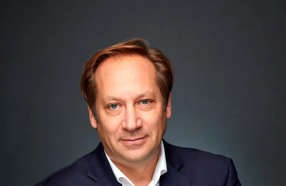 Man in a dark suit against a gray background