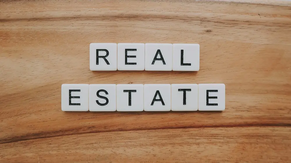 Scrabble tiles spelling out 'Real Estate' on wooden surface