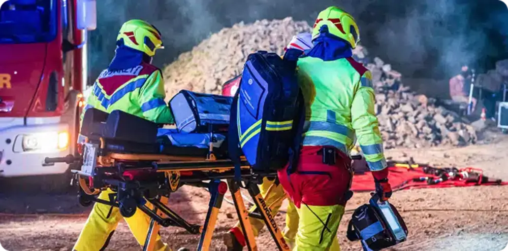 Rescue workers equipped and ready beside a stretcher at night