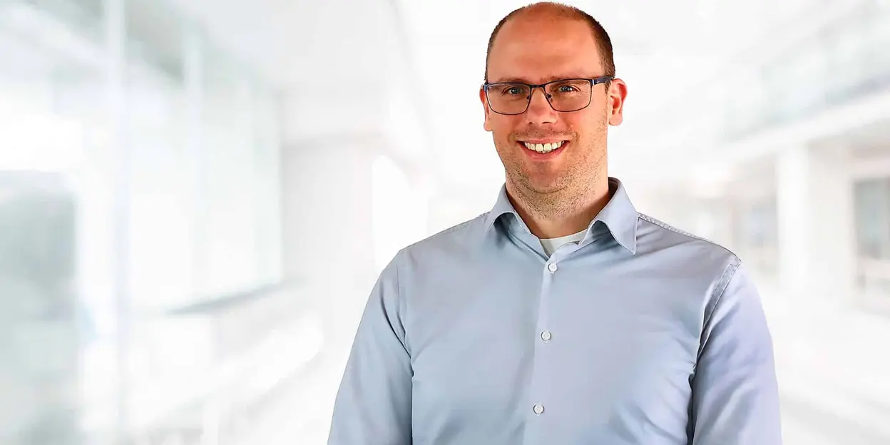Man with glasses smiling in a light-filled office