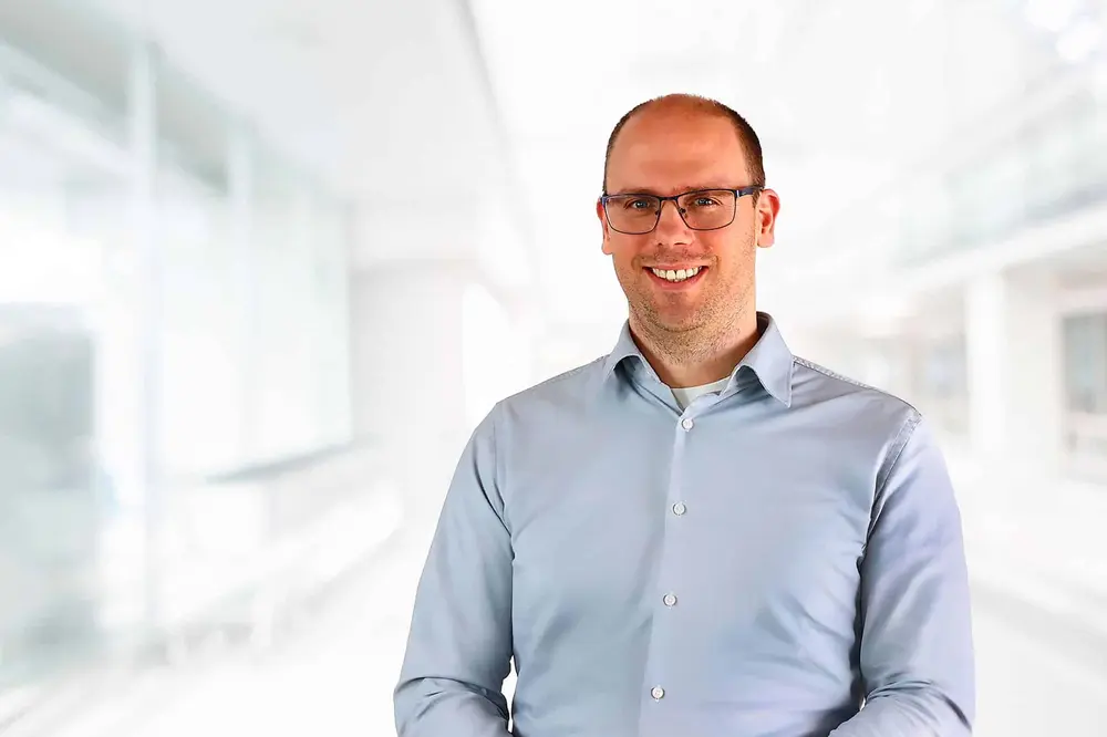 Man with glasses smiling in a light-filled office