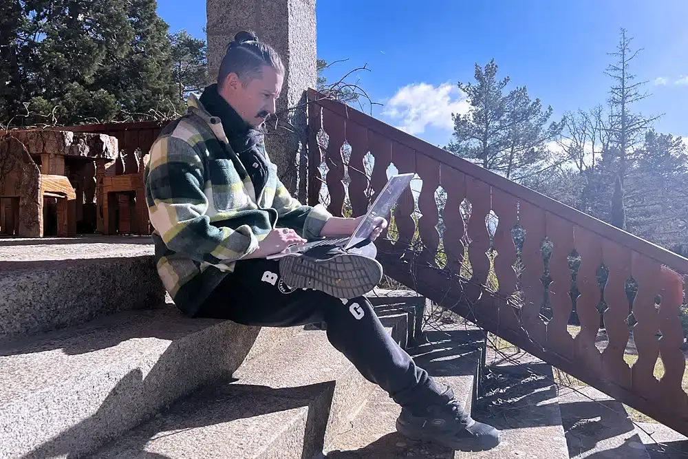 A man sitting on outdoor steps using a laptop