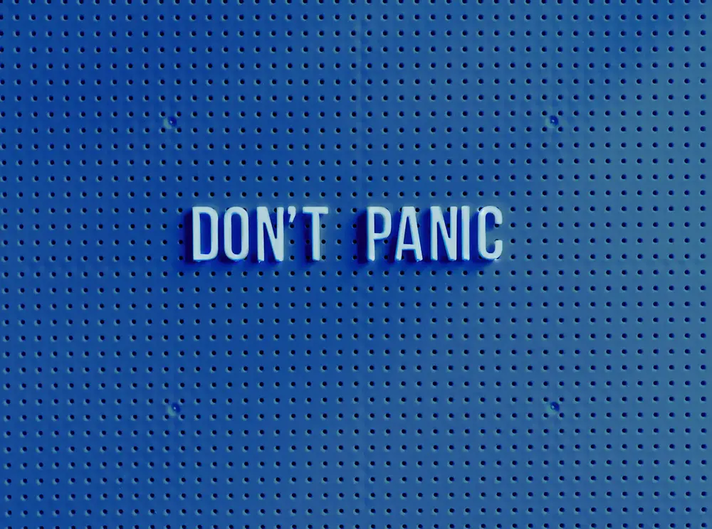 Lettering saying Don't Panic on a blue perforated surface