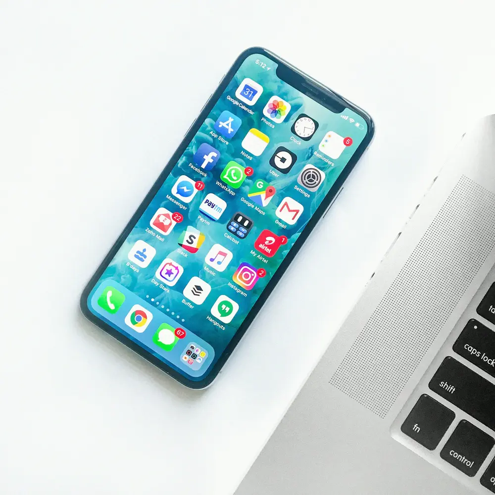 Smartphone with apps next to a laptop on white background